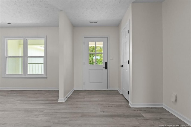 foyer with wood finished floors, a textured ceiling, and baseboards
