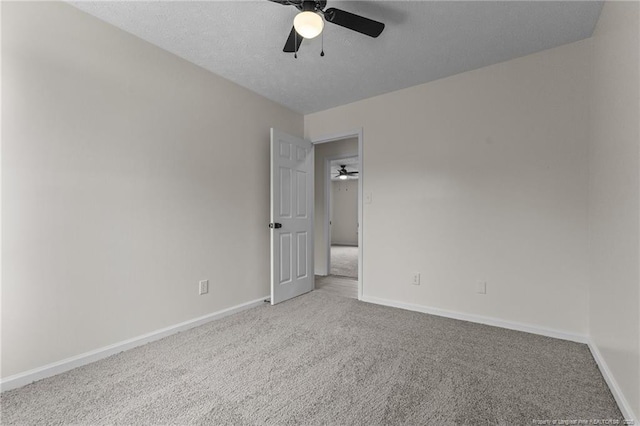 carpeted empty room featuring ceiling fan and baseboards