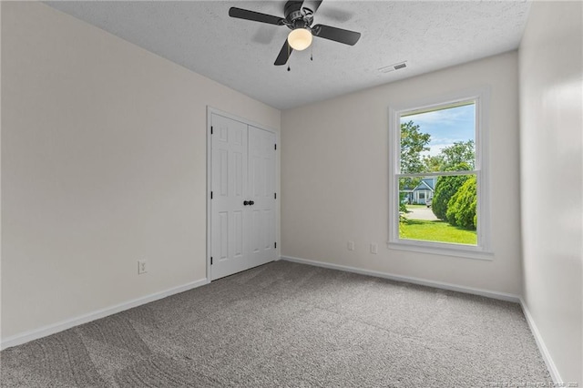 empty room with carpet flooring, baseboards, a textured ceiling, and ceiling fan