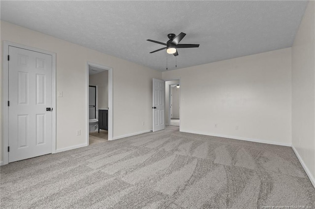 unfurnished bedroom with baseboards, carpet, a textured ceiling, and connected bathroom