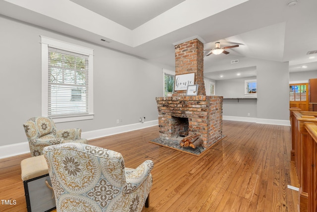 1008 Dorothea Dr, Raleigh, NC 27603 - living area featuring wood-type flooring, a brick fireplace, ceiling fan, baseboards, and vaulted ceiling