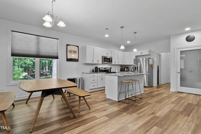 136 Hatchet Cv, Louisburg, NC 27549 - kitchen with stainless steel appliances, a kitchen island with sink, recessed lighting, light wood-type flooring, and white cabinets