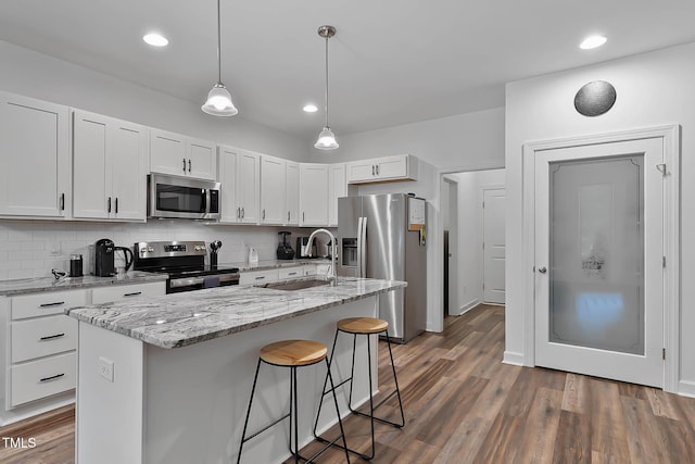 136 Hatchet Cv, Louisburg, NC 27549 - kitchen with stainless steel appliances, a sink, white cabinetry, decorative backsplash, and a kitchen breakfast bar