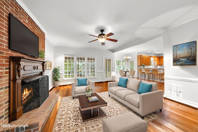 1007 Surry Dale Ct, Apex, NC 27502 - living room featuring light wood-style flooring, a ceiling fan, a brick fireplace, crown molding, and baseboards