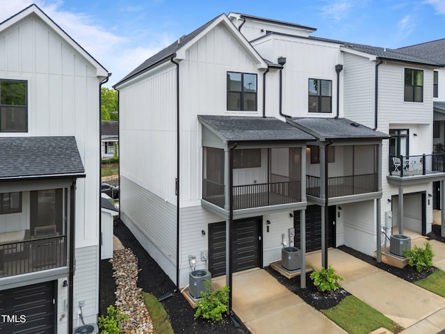 710 W N St Unit 101, Raleigh, NC 27603 - view of front facade featuring board and batten siding, a garage, a balcony, central AC, and a shingled roof