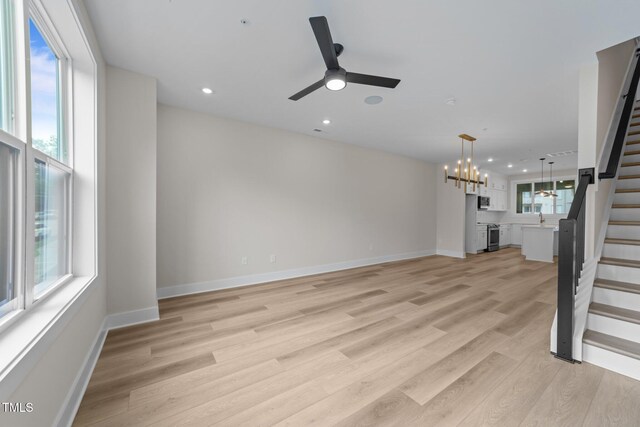 710 W N St Unit 101, Raleigh, NC 27603 - unfurnished living room with stairs, baseboards, light wood-style flooring, recessed lighting, and ceiling fan