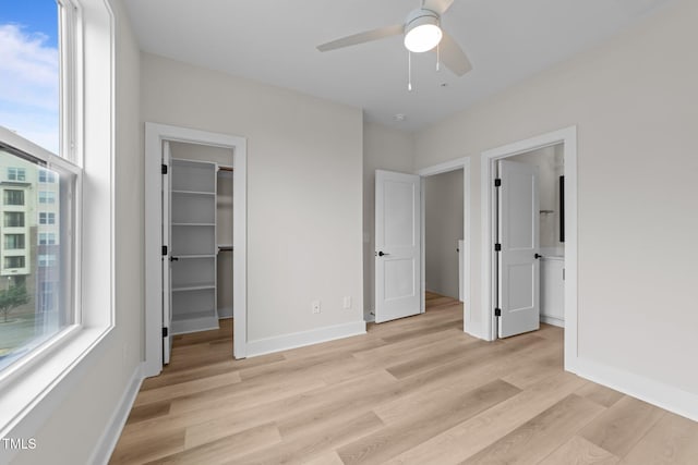 710 W N St Unit 101, Raleigh, NC 27603 - unfurnished bedroom featuring multiple windows, light wood-style floors, a spacious closet, and baseboards