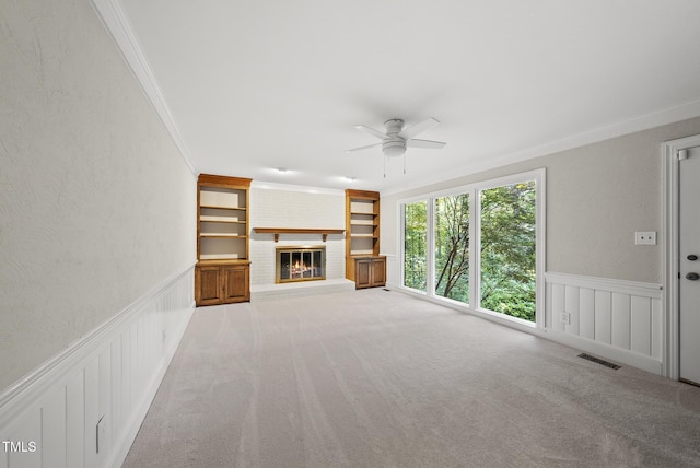 2300 Valley Forge Dr, Raleigh, NC 27615 - unfurnished living room featuring crown molding, ceiling fan, built in shelves, a fireplace, and a wainscoted wall