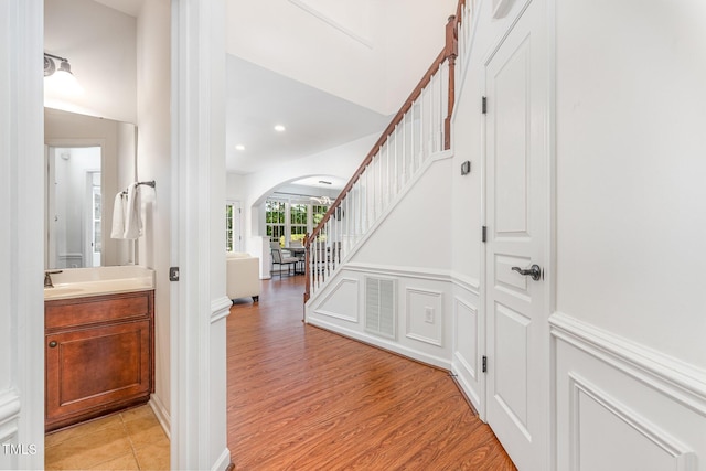 233 Hammond Wood Pl, Morrisville, NC 27560 - hall featuring arched walkways, stairway, recessed lighting, light wood-style floors, and a sink