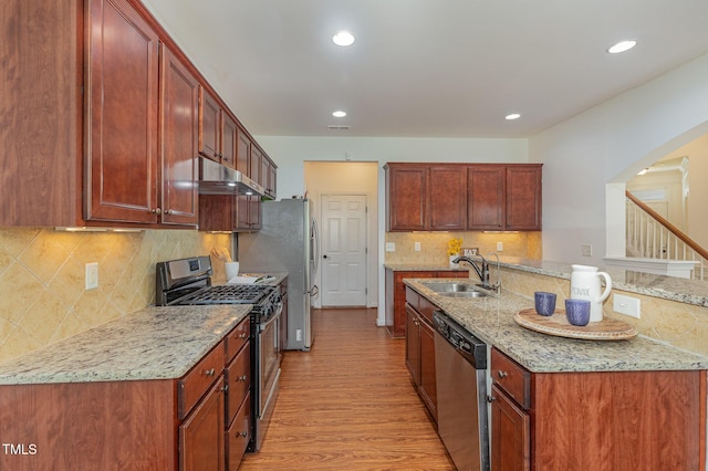 233 Hammond Wood Pl, Morrisville, NC 27560 - kitchen featuring stainless steel appliances, a sink, light wood-style flooring, under cabinet range hood, and decorative backsplash