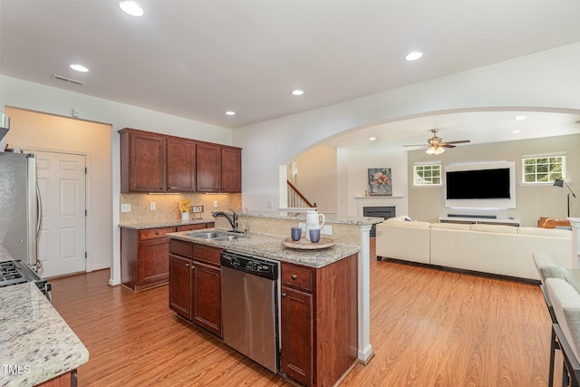 233 Hammond Wood Pl, Morrisville, NC 27560 - kitchen featuring appliances with stainless steel finishes, arched walkways, a ceiling fan, light wood-style flooring, and a fireplace