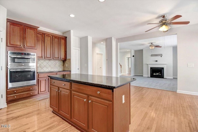 1420 Lagerfeld Way, Wake Forest, NC 27587 - kitchen featuring ceiling fan, stainless steel double oven, light wood finished floors, decorative backsplash, and a kitchen island
