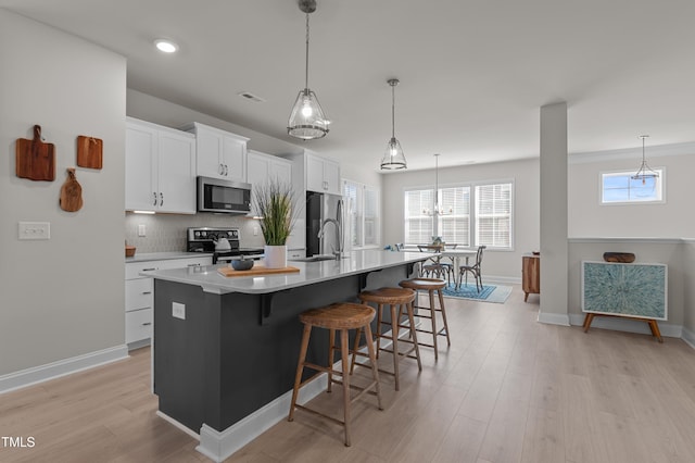 518 Toran Dr, Wake Forest, NC 27587 - kitchen featuring stainless steel appliances, an island with sink, a breakfast bar area, white cabinetry, and light wood-style floors