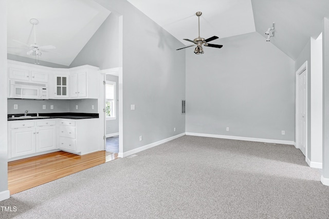 2709 Les Paul Ln, Apex, NC 27539 - unfurnished living room featuring ceiling fan, light carpet, high vaulted ceiling, a sink, and baseboards