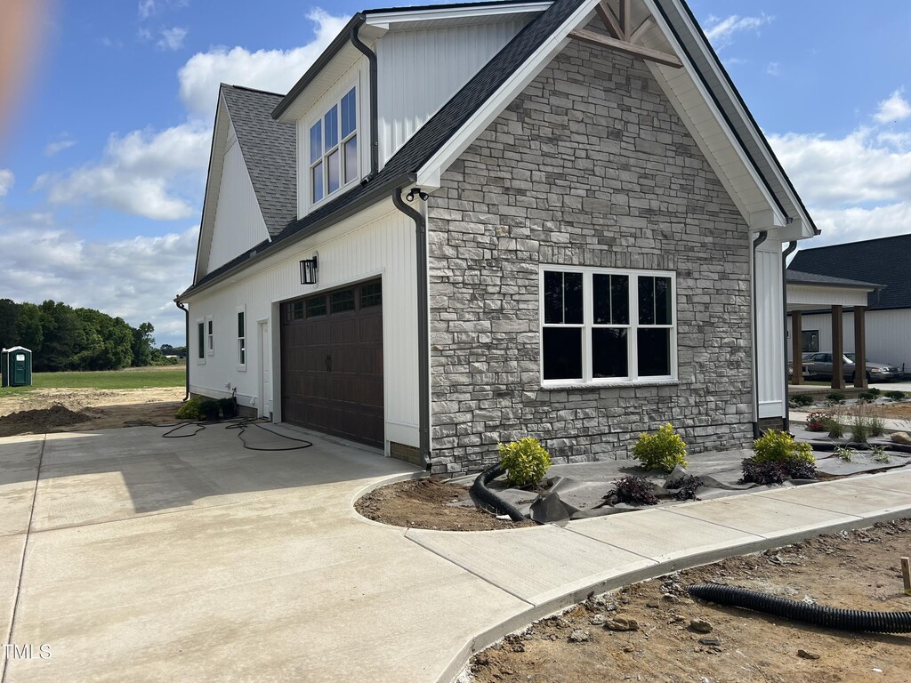 188 Banner Elk Rd, Benson, NC 27504 - view of property exterior featuring stone siding, concrete driveway, roof with shingles, and a garage