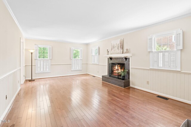 2107 Somers Ave, Burlington, NC 27215 - unfurnished living room featuring wainscoting, wood finished floors, ornamental molding, and a brick fireplace