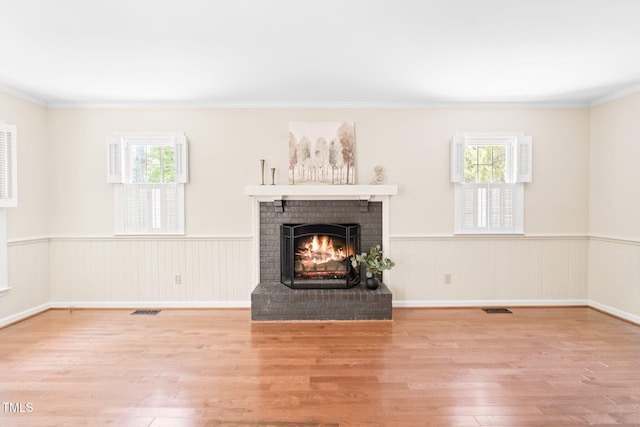 2107 Somers Ave, Burlington, NC 27215 - unfurnished living room with wood finished floors, a brick fireplace, wainscoting, healthy amount of natural light, and ornamental molding