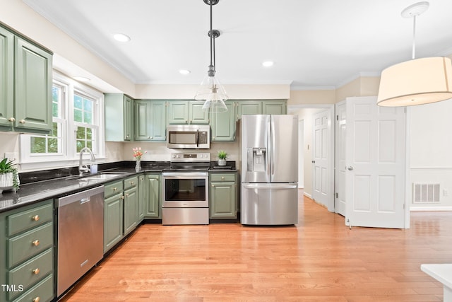 2107 Somers Ave, Burlington, NC 27215 - kitchen featuring appliances with stainless steel finishes, green cabinetry, a sink, dark countertops, and ornamental molding