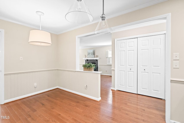 2107 Somers Ave, Burlington, NC 27215 - unfurnished dining area featuring light wood-style flooring, crown molding, a wainscoted wall, and a brick fireplace