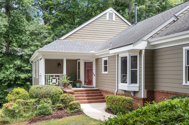 108 Ripplewater Ln, Cary, NC 27518 - view of front facade with a shingled roof, brick siding, covered porch, and view of scattered trees