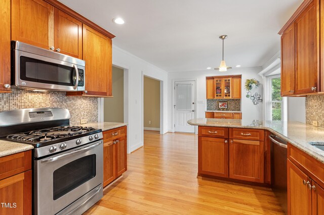 108 Ripplewater Ln, Cary, NC 27518 - kitchen featuring appliances with stainless steel finishes, decorative backsplash, a peninsula, brown cabinets, and light wood finished floors
