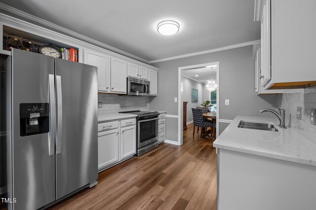 166 Greenmont Ln, Cary, NC 27511 - kitchen with stainless steel appliances, a sink, white cabinetry, backsplash, and ornamental molding