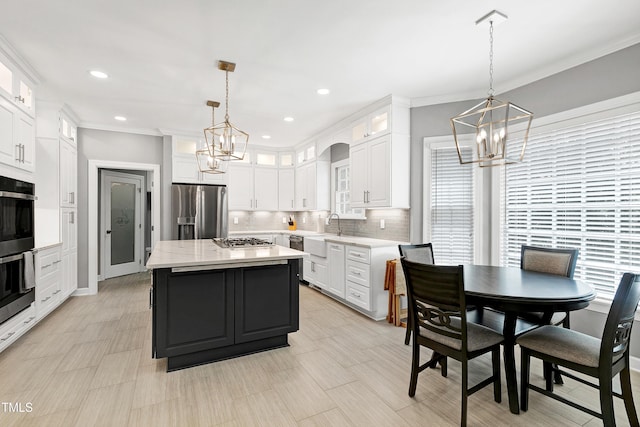 225 Midenhall Way, Cary, NC 27513 - kitchen featuring appliances with stainless steel finishes, a chandelier, white cabinetry, tasteful backsplash, and crown molding
