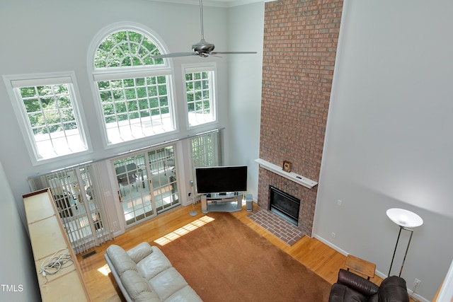 225 Midenhall Way, Cary, NC 27513 - living room featuring a high ceiling, wood finished floors, a ceiling fan, and a fireplace with flush hearth