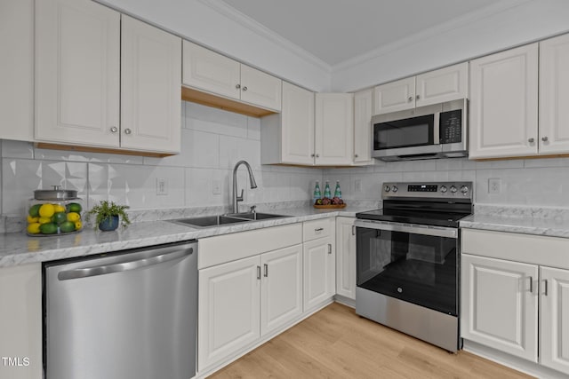 1204 Pecan Pl, Durham, NC 27704 - kitchen featuring stainless steel appliances, a sink, crown molding, white cabinets, and decorative backsplash