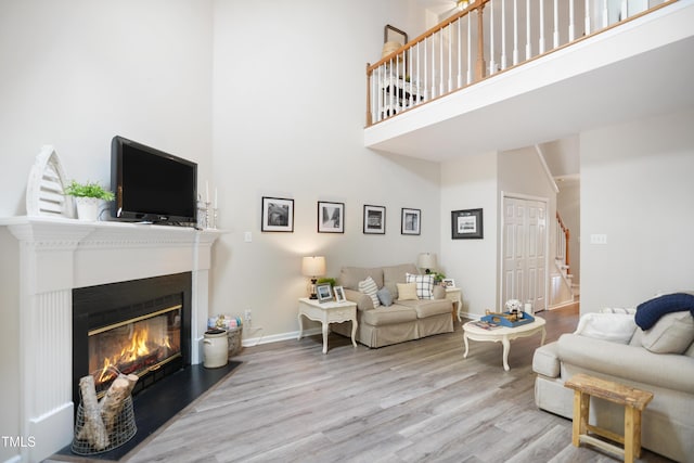 114 Colchis Ct, Cary, NC 27513 - living room featuring a high ceiling, stairway, wood finished floors, a fireplace with flush hearth, and baseboards