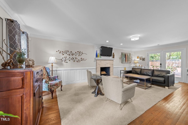 2901 Ceremonial Ct, Raleigh, NC 27615 - living room featuring ornamental molding, light wood finished floors, a fireplace, wainscoting, and a decorative wall