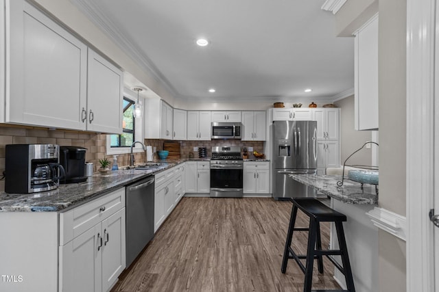 2901 Ceremonial Ct, Raleigh, NC 27615 - kitchen featuring stainless steel appliances, a sink, ornamental molding, dark wood-type flooring, and white cabinetry