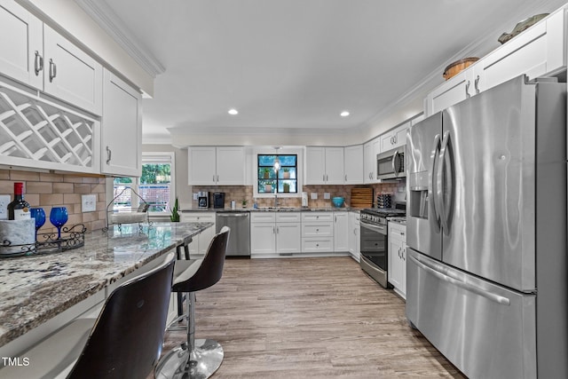 2901 Ceremonial Ct, Raleigh, NC 27615 - kitchen with appliances with stainless steel finishes, crown molding, light stone counters, decorative backsplash, and white cabinets