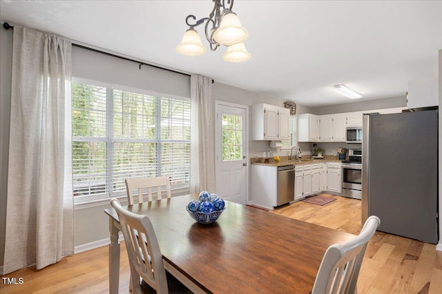 4520 Timberhurst Dr, Raleigh, NC 27612 - dining area featuring a chandelier, light wood-style floors, and baseboards