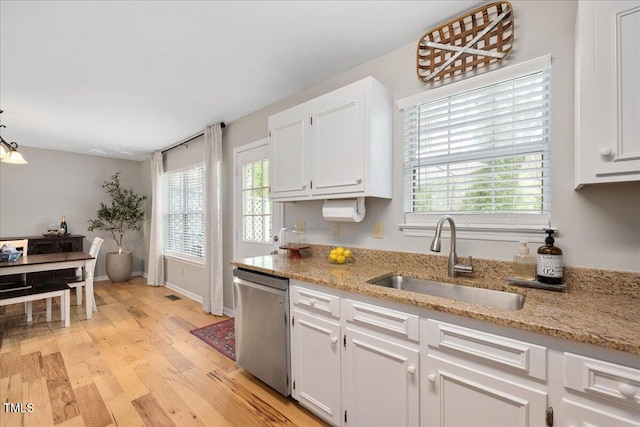 4520 Timberhurst Dr, Raleigh, NC 27612 - kitchen with stainless steel dishwasher, a sink, white cabinets, light wood finished floors, and light stone countertops