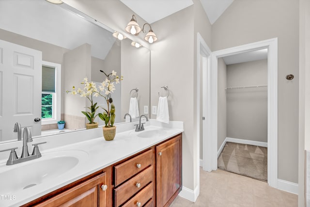 8140 Consella Way, Willow Springs, NC 27592 - bathroom featuring double vanity, vaulted ceiling, a walk in closet, tile patterned floors, and baseboards