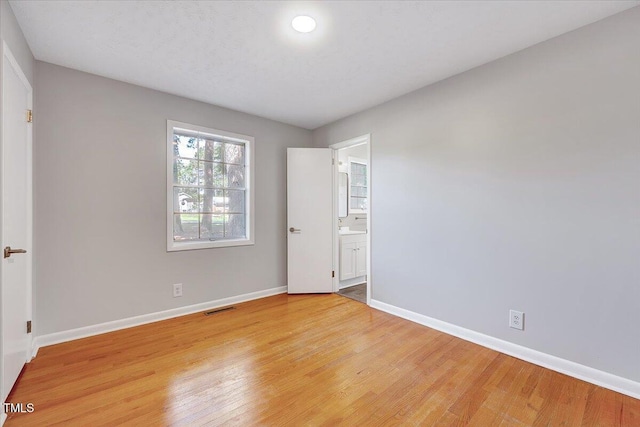 8004 Summit Dr, Goldsboro, NC 27530 - unfurnished bedroom with light wood finished floors, baseboards, and ensuite bath