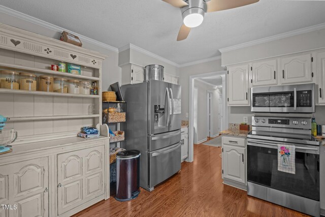 815 Walter Bright Rd, Sanford, NC 27330 - kitchen with stainless steel appliances, wood finished floors, ceiling fan, ornamental molding, and white cabinets