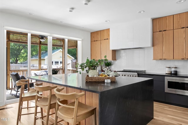 1405 Watts St, Durham, NC 27701 - kitchen with modern cabinets, stainless steel microwave, a breakfast bar area, a kitchen island, and recessed lighting