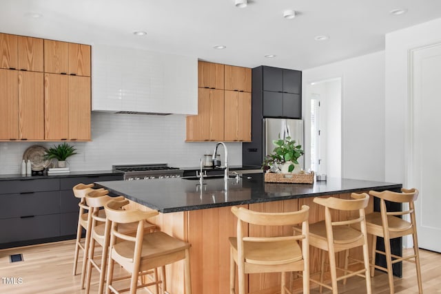 1405 Watts St, Durham, NC 27701 - kitchen with a sink, freestanding refrigerator, backsplash, light wood-style floors, and an island with sink
