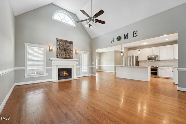 105 Bagley Ln, Dunn, NC 28334 - unfurnished living room featuring high vaulted ceiling, ceiling fan, a fireplace with flush hearth, light wood-style flooring, and baseboards
