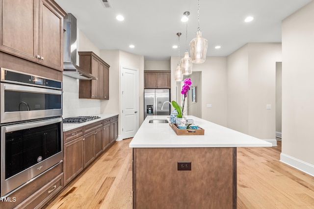 192 Glenpark Pl, Cary, NC 27511 - kitchen with wall chimney exhaust hood, stainless steel appliances, light wood-style flooring, an island with sink, and recessed lighting