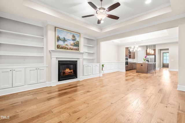 192 Glenpark Pl, Cary, NC 27511 - unfurnished living room with light wood finished floors, a raised ceiling, a glass covered fireplace, a ceiling fan, and a chandelier