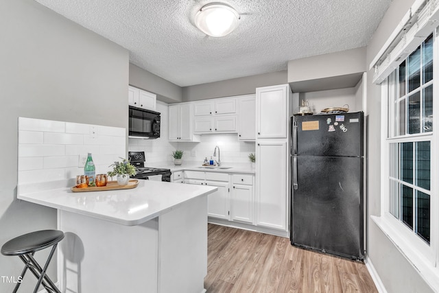 501 Gooseneck Dr Unit B2, Cary, NC 27513 - kitchen featuring black appliances, a sink, a peninsula, a textured ceiling, and white cabinets