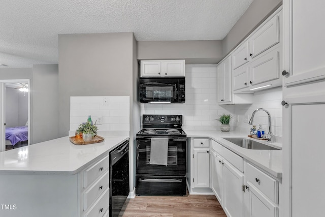 501 Gooseneck Dr Unit B2, Cary, NC 27513 - kitchen featuring black appliances, a sink, a peninsula, a textured ceiling, and white cabinets