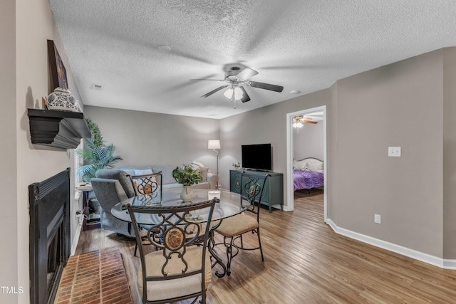 501 Gooseneck Dr Unit B2, Cary, NC 27513 - dining area featuring a ceiling fan, light wood-style floors, a fireplace, baseboards, and a textured ceiling