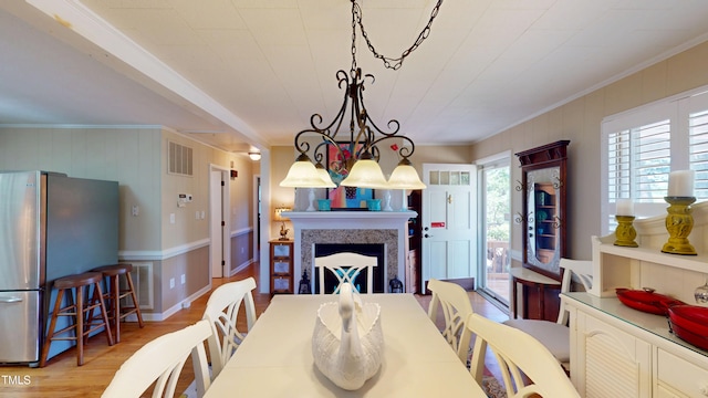 4509 Stevens Chapel Rd, Smithfield, NC 27577 - dining room featuring ornamental molding, a decorative wall, light wood-type flooring, a fireplace, and a chandelier