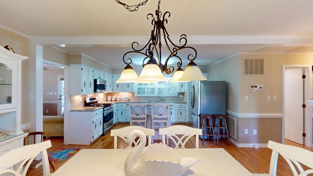 4509 Stevens Chapel Rd, Smithfield, NC 27577 - dining space with light wood finished floors, ornamental molding, a chandelier, plenty of natural light, and beamed ceiling