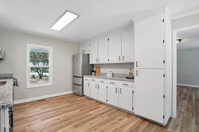 3916 W Allen, Raleigh, NC 27603 - kitchen with freestanding refrigerator, light wood-style floors, white cabinets, light stone countertops, and baseboards