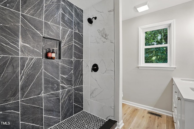3916 W Allen, Raleigh, NC 27603 - bathroom featuring vanity, wood finished floors, a tile shower, and baseboards